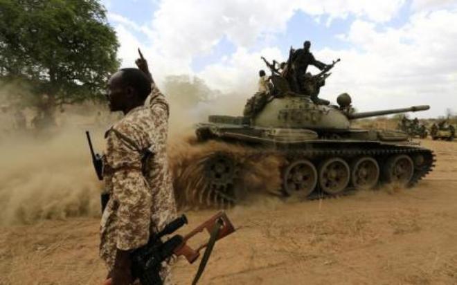 A military personnel gestures next to a tank after the Sudanese Armed Forces (SAF) and the Rapid Support Forces (RSF) recaptured the Daldako area, outside the military headquarters in Kadogli May 20, 2014.